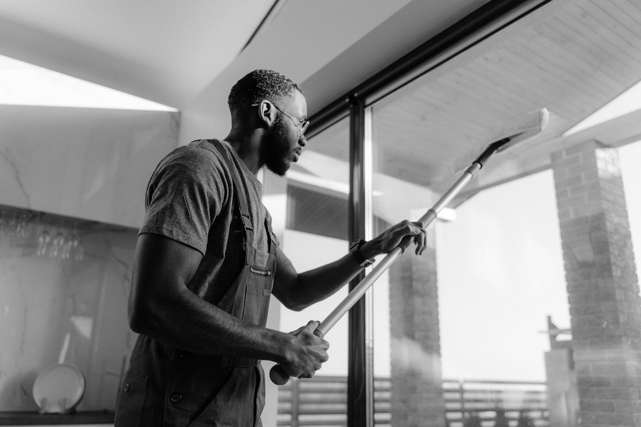 services-03 A professional cleaner wiping large glass panels with precision inside a modern building.