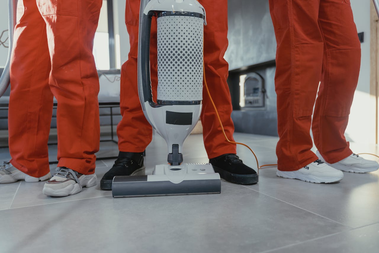 hero-img Team of professional cleaners in red uniforms using a vacuum cleaner indoors.